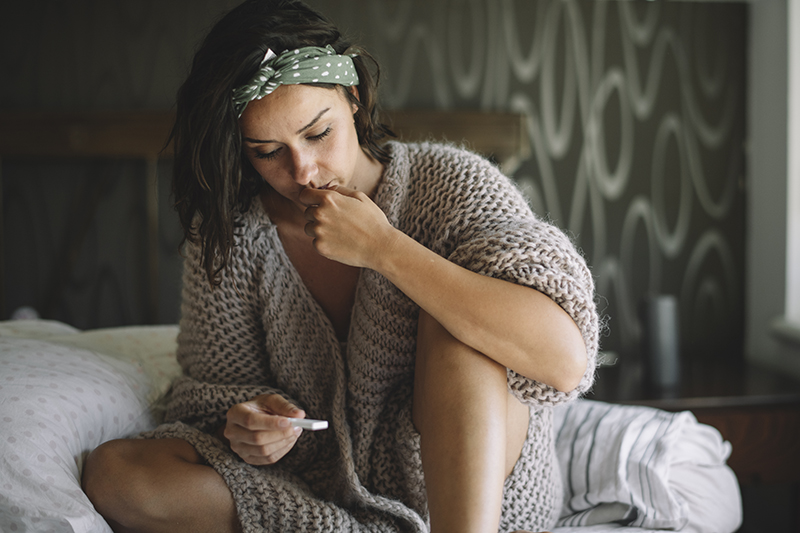 young woman looking at pregnancy test with concern